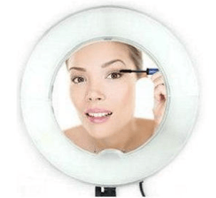 Woman applying mascara looking into ring light mirror